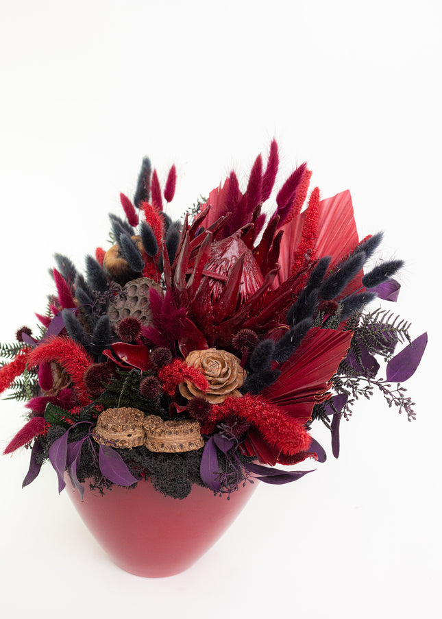 Aranjament Floral „Scarlet Royalty” în Vas Bordo – Compoziție Luxury cu Protea King, Evantai Palmier și Accente Negru Abis