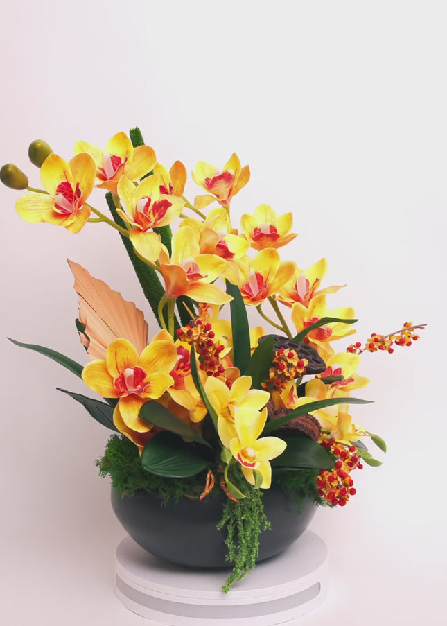 Aranjament Floral „Solar Orchid” în Vas Ceramic Negru – Decor de Lux cu Orhidee Galbene, Ilex și Accente Botanice Exotice