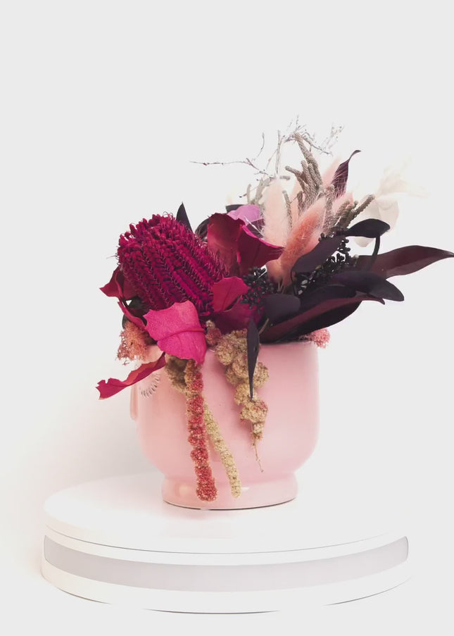Aranjament Floral „Pink Reverie” în Vas Sculptural Roz – Decor Handmade cu Banksia Purpurie, Flori Criogenate și Accente Catifelate