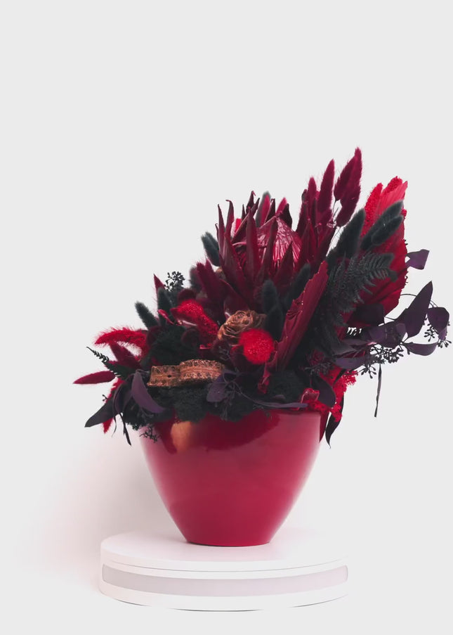 Aranjament Floral „Scarlet Royalty” în Vas Bordo – Compoziție Luxury cu Protea King, Evantai Palmier și Accente Negru Abis